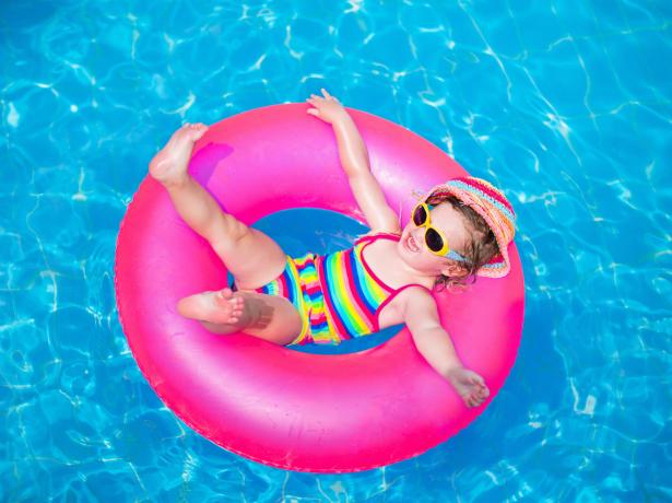 Happy child on a pink float in the pool.