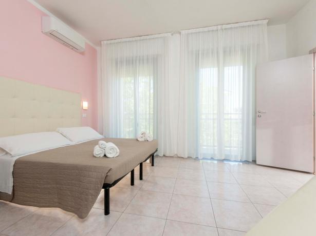 Bright room with double bed and white curtains.