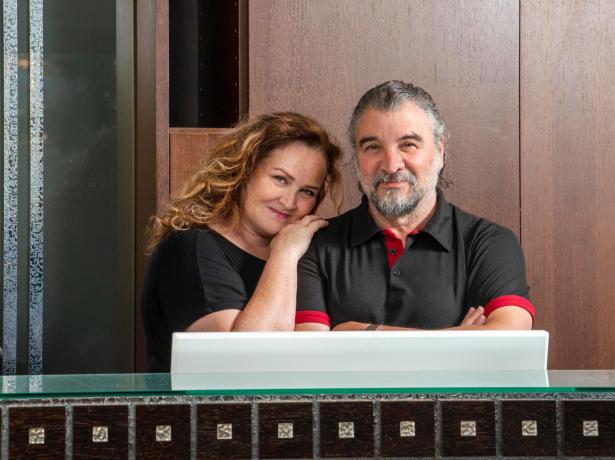 Smiling couple in front of a wooden counter.