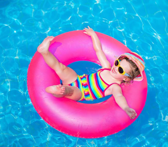 Glückliches Kind auf einem rosa Schwimmring im Pool.