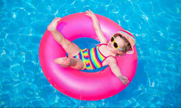 Happy child on a pink float in the pool.