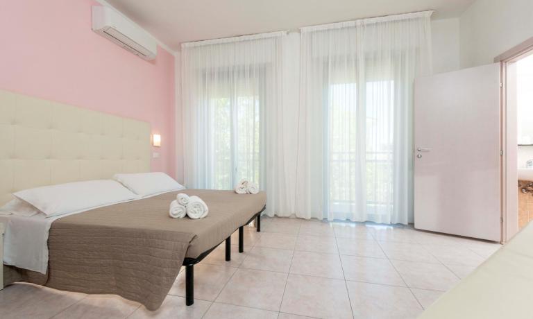 Bright room with double bed and white curtains.